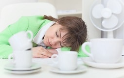 Woman has got tired and sleeps on table among coffee cups