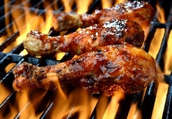 grilling chicken on barbecue with flames