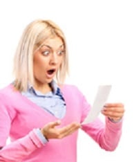 A surprised woman looking at store receipt and holding a shoppin