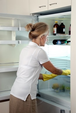 Seniorin putzt Kühlschrank